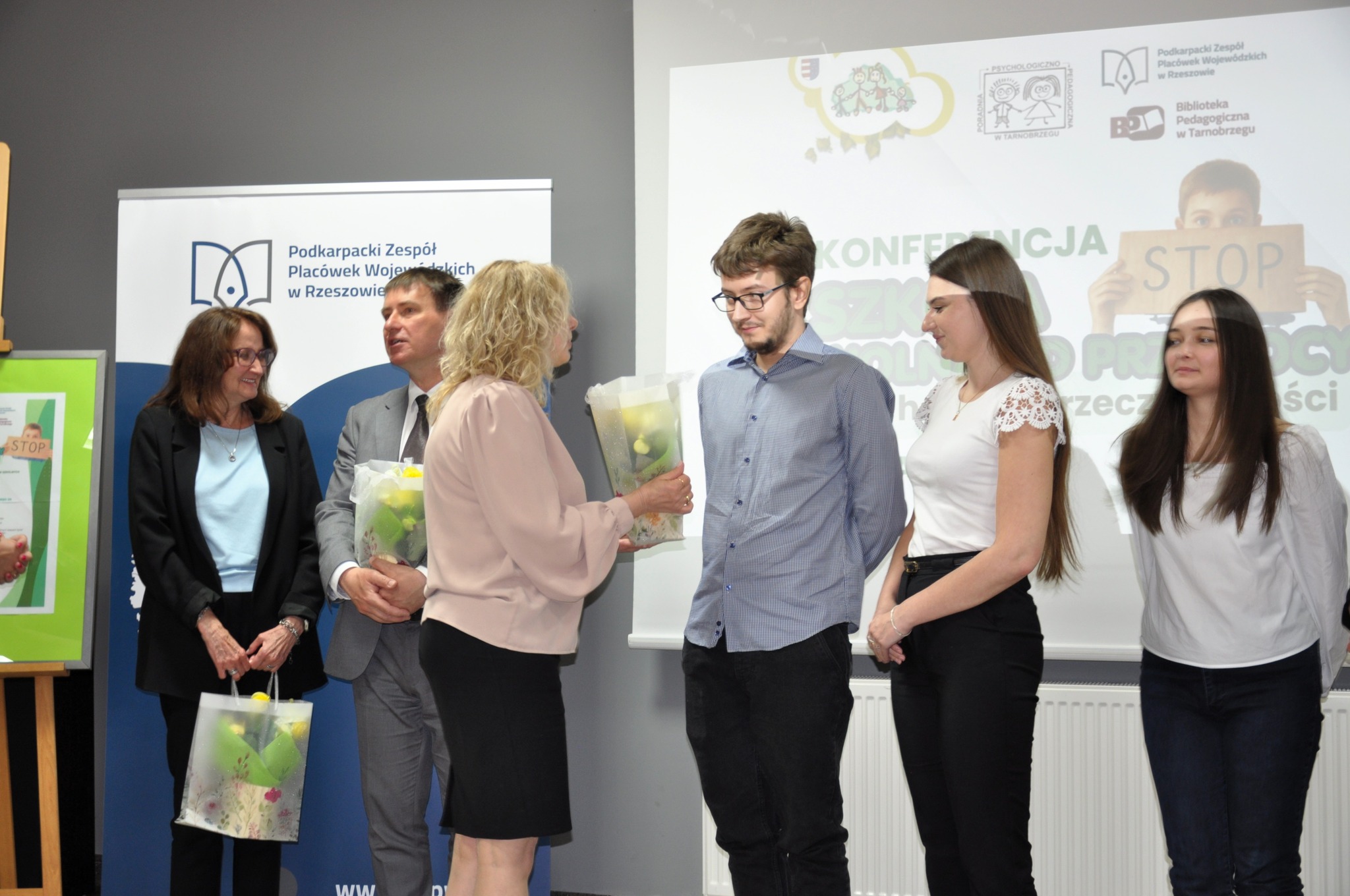 zdjęcie przedstawia studentów i osoby wręczające nagrody na tle ekranu